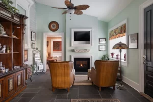 Tasteful, soft green living room area with antique wooden furniture and double-sided fireplace