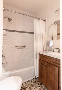 Private bathroom for The Canopy Room with white tile shower and cobblestone-style floor