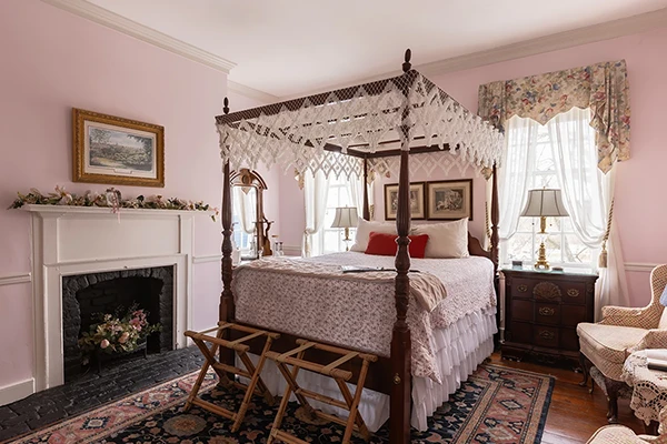 Canopy bed in a beautiful, feminine, pink bedroom with a fireplace