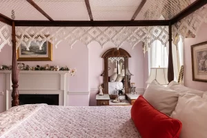 View across bed of fireplace and cute antique vanity with mirror in Canopy bedroom