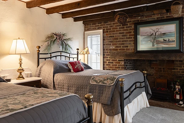 Kitchen House bedroom with brick wall and fireplace, exposed beam ceiling, window, and two beds