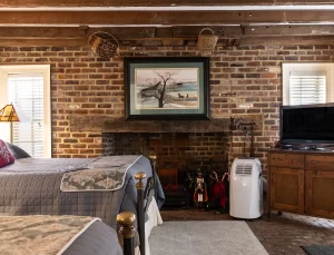 Kitchen House bedroom with brick wall and fireplace, exposed beam ceiling, window, and two beds