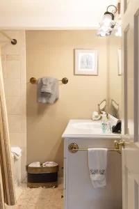 The Loft khaki-colored bathroom with tiled shower / tub and brass hardware.
