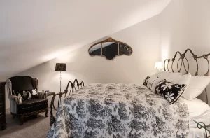The Loft bedroom with black and white furniture, unique antique mirror, and angled ceiling