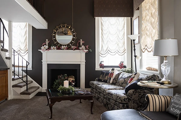 The Loft earth tones colored living room area with couch, decorative fireplace, and windows