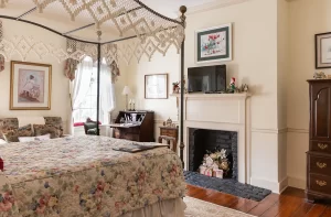 Olivia's room cream and green colored bedroom with decorative fireplace, desk, window, and seating area